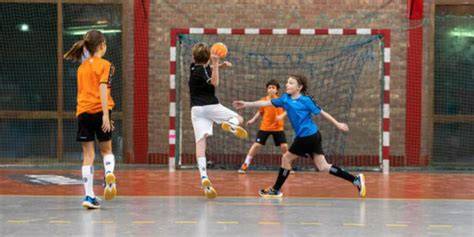 Dos niños jugando handball en cancha
