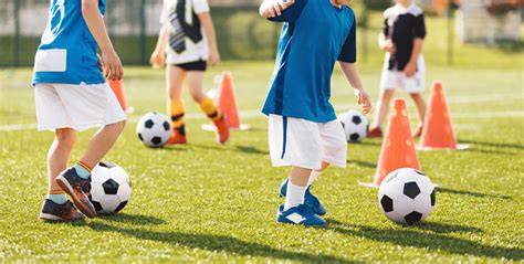 Niños botando balones en media pista